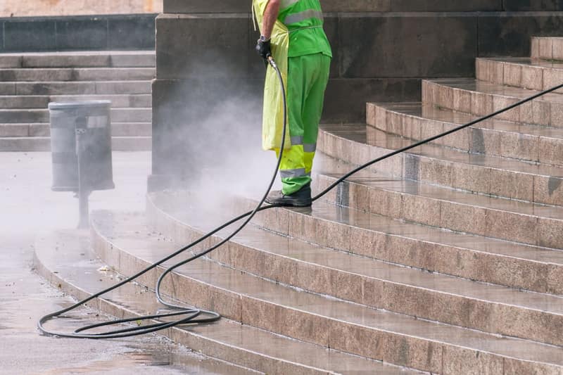 Worker pressure washing outdoor steps