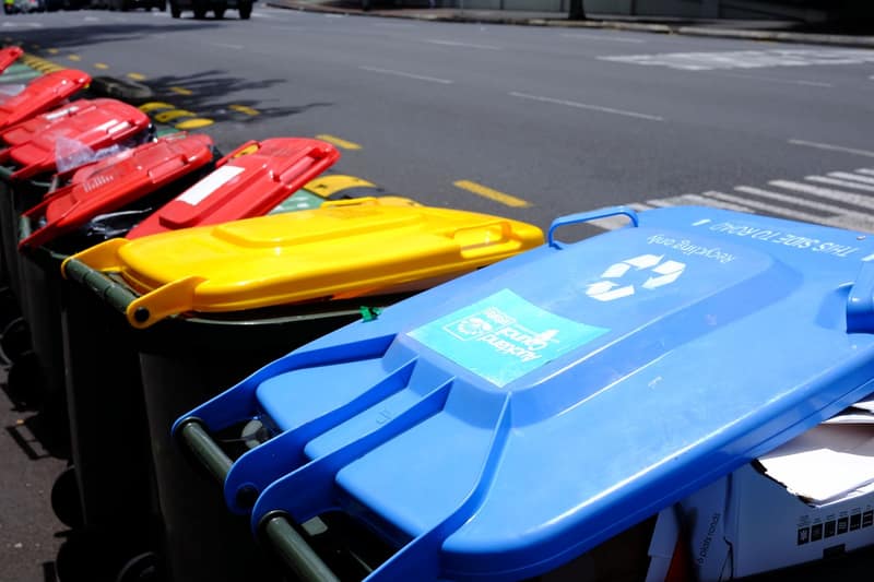Colorful recycling bins lined up on a sunny street