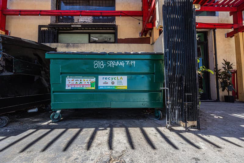 Green commercial dumpster outside a building