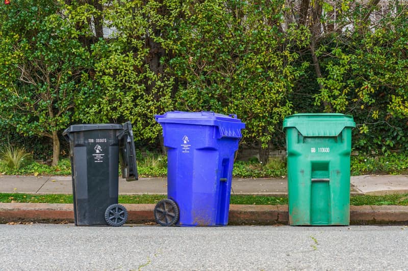 Black, blue and green bins lined up at the curb ready for collection