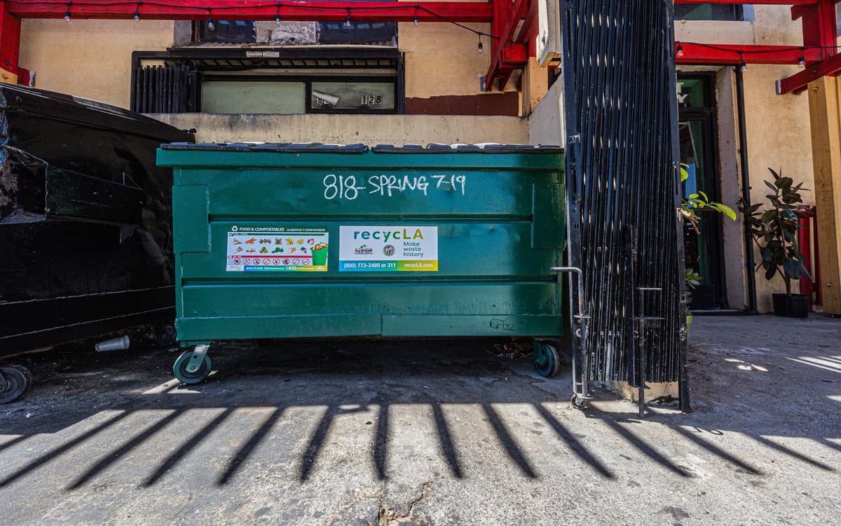 Green commercial dumpster outside a building
