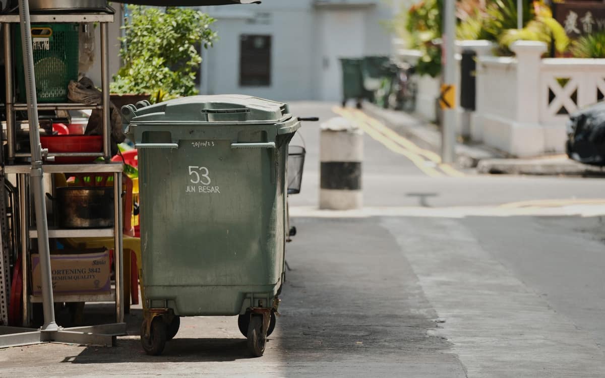 Green garbage cart on a quiet street in sunlight