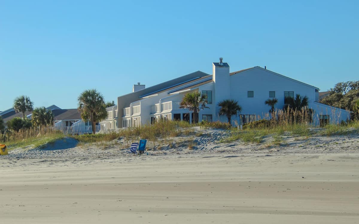 Beachfront houses with palm trees under a clear sky